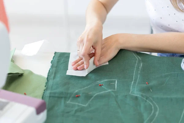 一位年轻的女设计师的手为坐在缝纫机旁边的桌子旁的缝纫产品做标记。创意业务与设计理念. — 图库照片
