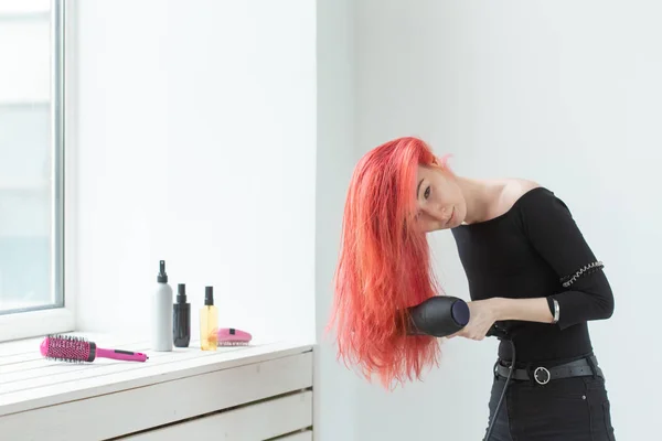 Hairdresser, beauty salon and people concept - young woman hair stylist with hair dryer on white background — Stock Photo, Image