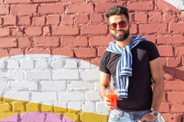 Sıcak güneşli bir yaz gününde şehirde yürürken bir saman ile meyve suyu ile olumlu neşeli bir genç Arap adam Portresi. Çalışma sonrası dinlenme kavramı ve hafta sonları çalışma.