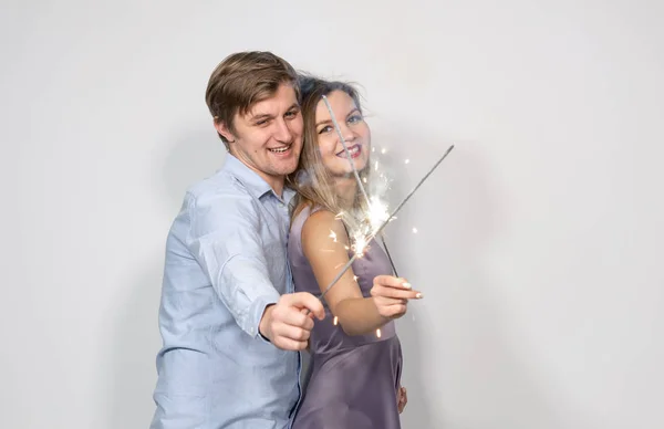 Festa, ano novo, conceito de Natal e feriados - jovem casal celebrando seu aniversário com faíscas no fundo branco — Fotografia de Stock