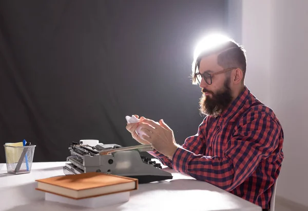 Gente y concepto de tecnología - Día Mundial del escritor, hombre guapo con barba trabajando en la máquina de escribir sobre fondo negro — Foto de Stock