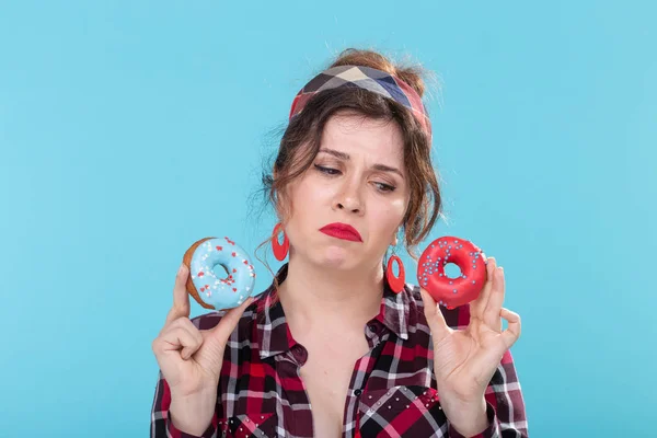 Дурна їжа, дієта та концепція здорового способу життя - пін-ап жінка з пончиками на синьому фоні — стокове фото