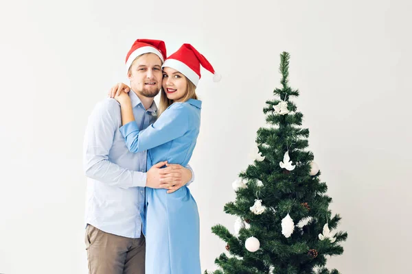 Albero di Natale e concetto di vacanze - Felice famiglia sorridente indossa cappelli di Babbo Natale che celebrano a casa . — Foto Stock