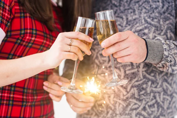 Handen dicht met sterretjes en champagneglazen. Vuurwerk vieren 's nachts gelukkig nieuwjaar — Stockfoto
