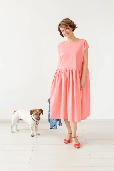 pet and people concept - young woman in pink dress with jack russell over the white background