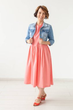 Uzun zarif bir elbise ve onun sevgili köpek Jack Russell Terrier ile beyaz bir arka plan üzerinde poz bir kot gömlek Pretty genç kadın. Günlük şık görüntü kavramı.