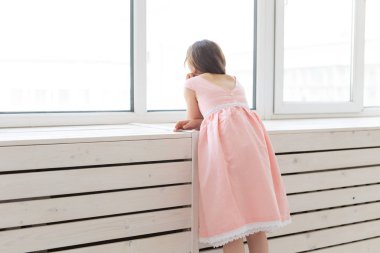 Yemyeşil şeftali prenses elbise büyüleyici küçük kız odasının penceresinden dışarı bakar. Çocuk arzuları ve bir mucize beklentileri kavramı.