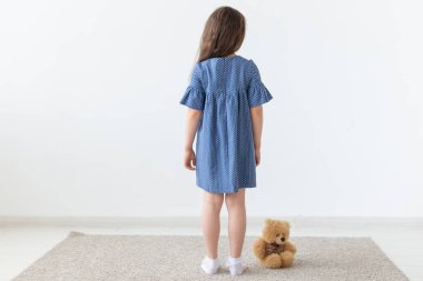 Beyaz odadaki mavi elbiseli, oyuncaklı kızın arka planı.
