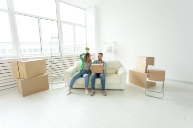 Neşeli neşeli genç çift büyüleyici kız ve yeni bir daireye hareket ederken bir bitki ile şeyler ve bir pot ile bir kutu tutan yakışıklı adam. Ev ve mortgage konsepti.