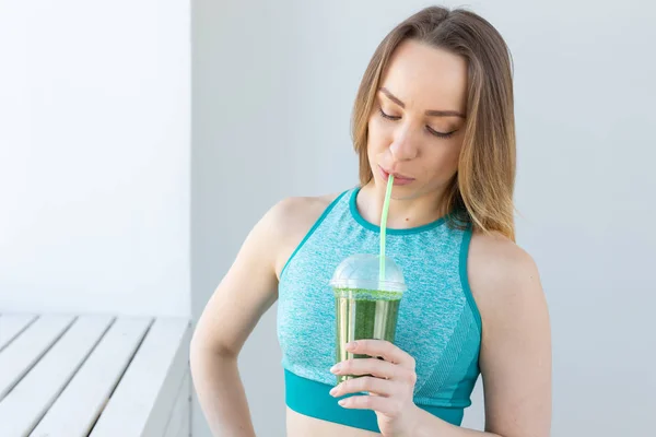 stock image Healthy, fitness and detox concept - close up of young woman in sports wear with green smoothie indoors