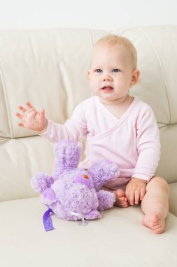 çocukluk, bebeklik ve insan kavramı - evde kanepede oturan mutlu küçük bebek kız