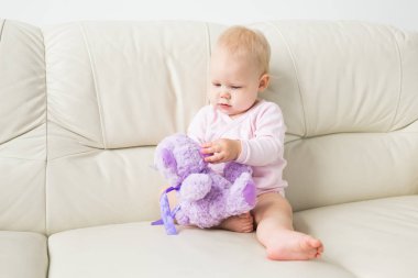 Çocuklar, bebek ve çocukluk konsepti - Güzel sevimli yumuşak bebek kanepede oturan