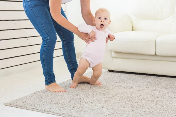 Primeros pasos del bebé pequeño aprendiendo a caminar en la sala de estar soleada blanca. Calzado para niños . — Foto de Stock