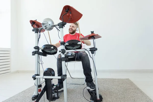 Mensen, muziek en hobby concept-stoere man in rood t-shirt en zwarte sneakers spelen elektronische drum kit — Stockfoto