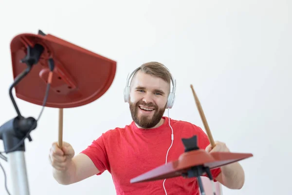 Trummis, hobbyer och musikkoncept-Young man Drummer i röd skjorta spelar den elektroniska trummor — Stockfoto