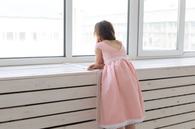 Çocuk, çocuk ve moda konsepti - küçük kız stüdyoda giysi pencereyakınında poz