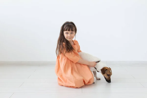 Barn och husdjur Concept-liten barnflicka i orange klänning spela med Jack Russell Terrier — Stockfoto