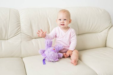 Çocuklar, bebek ve çocukluk konsepti - Güzel sevimli yumuşak bebek kanepede oturan