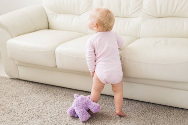 Çocuklar, bebek ve çocukluk konsepti - Güzel sevimli yumuşak bebek oturma odasında oynarken