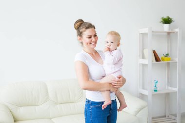 Genç mutlu sevgi dolu anne pencereye karşı kollarında onun bebek kızı tutarak. Anne bakımı. Çocuk bakımı.