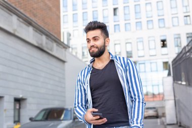 Sokakta cep telefonu ile Modern Arap genç adam. Dış mekan portresi.