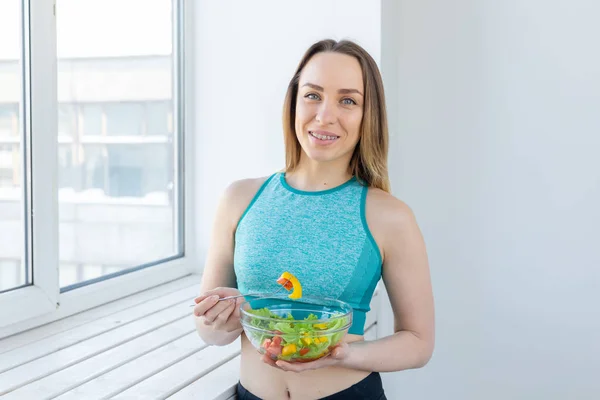 Zdrowy styl życia, fitness i dieta koncepcja-Sałatka dietetyczna i szczupła kobieta w sporcie nosić w pobliżu okna — Zdjęcie stockowe