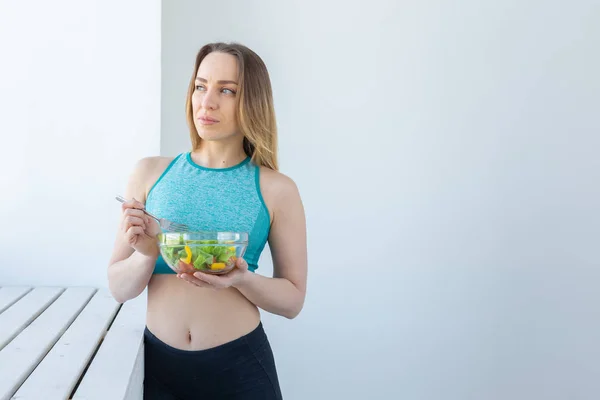 Stile di vita sano, fitness e dieta concetto - insalata dietetica e donna in abbigliamento sportivo, spazio copia — Foto Stock