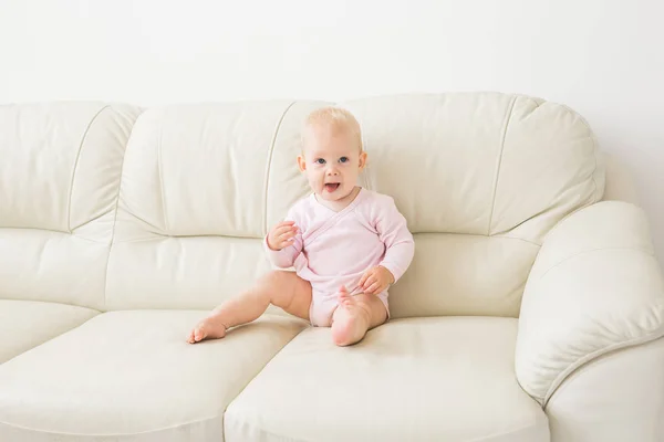 Childhood, babyhood and people concept - happy little baby girl sitting on couch at home — Stock Photo, Image