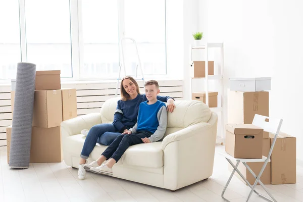 Schattige alleenstaande moeder en kleine jongen zoon ontspannen na de verhuizing. Het concept van een Inwijdingsfeest hypotheek en de vreugde van nieuwe woningen. — Stockfoto