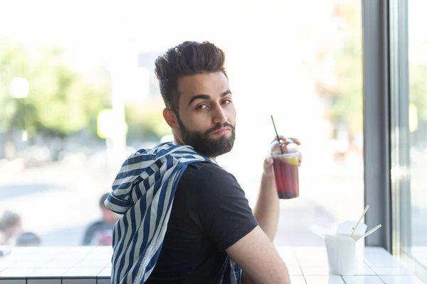 Retrato de un hombre árabe guapo bebiendo batido en un café. El concepto de descanso y descanso — Foto de Stock