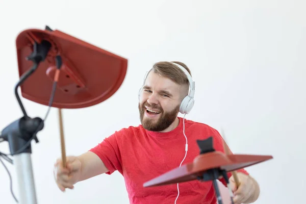 Trummis, hobbyer och musikkoncept-Young man Drummer i röd skjorta spelar den elektroniska trummor — Stockfoto