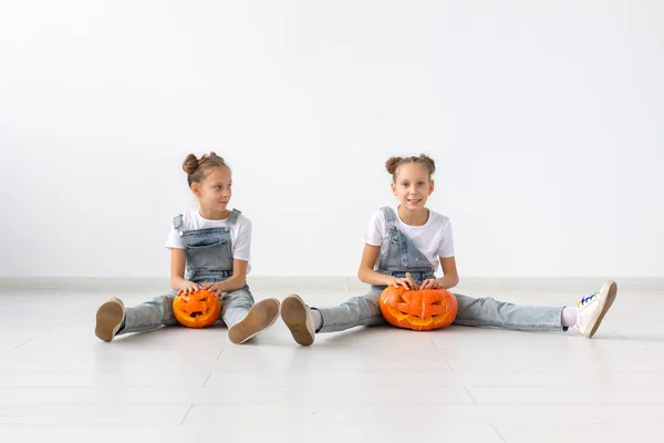 Buon Halloween, vacanze e concetto di infanzia - Carino gemelle sorelle ragazze con una zucca Jack-o-lanterna divertirsi mentre trascorre del tempo in casa — Foto Stock