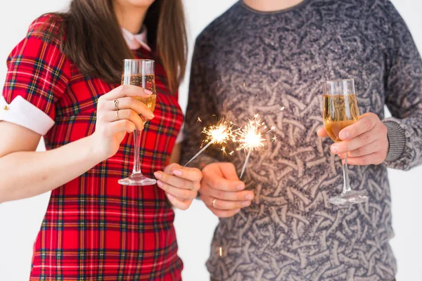 Fechar as mãos segurando brilhos e taças de champanhe. Fogos de artifício celebram à noite feliz ano novo — Fotografia de Stock