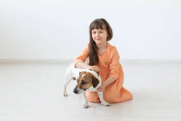 Děti a domácí zvířata koncept-malá holčička, která sedí na podlaze s roztomilým štěňátka Jack Russell teriér — Stock fotografie
