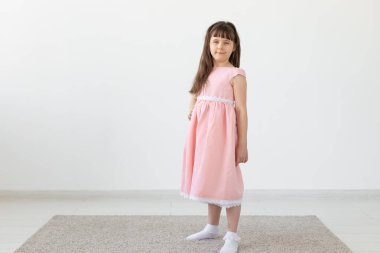 Pembe bir elbise beyaz bir arka plan üzerinde poz güzel küçük esmer kız. Sevimli çocuklar kavramı. Kopyalama alanı