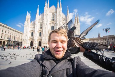 Kış seyahat, tatil ve kuşlar kavramı - selfie güvercinler yakınındaki Milan Katedrali Duomo di Milano, İtalya ile alarak genç komik adam.