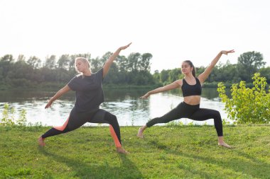 Parkta açık havada rahatlatıcı yoga keyfi kadın arkadaşlar.