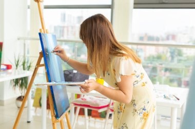 resim sanat sınıfları. çizim dersleri. beceri hayal gücü ve ilham. Şövale üzerinde resim oluşturma Büyüleyici öğrenci kız.