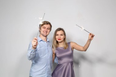 Kutlama, parti ve tatil kavramı - mutlu erkek ve kadın havai fişekleri ile gri arka plan üzerine sarılma