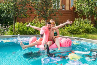 Ekoloji kavramı - Genç adam ve kadın çevre kirlenirken eğleniyor, suda yüzen plastik çöp ile küresel sorun kavramı.