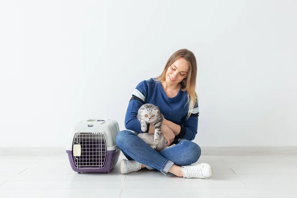 Charmante jeune femme positive tient dans ses mains son beau chat écossais pli gris assis sur le sol dans un nouvel appartement. Concept animal de compagnie . — Photo