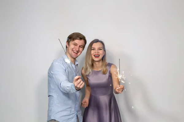 Conceito de feriados, festas e celebrações - jovem casal com brilhos no fundo branco — Fotografia de Stock