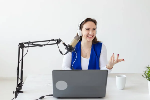 Concepto de presentador de radio - Mujer trabajando como presentadora de radio sentada frente al micrófono sobre fondo blanco en el estudio — Foto de Stock