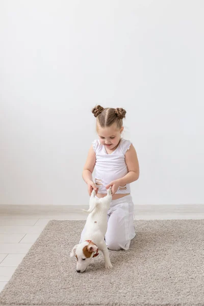 Mascotas, niños y concepto animal - Niña sosteniendo un cachorro por las patas — Foto de Stock