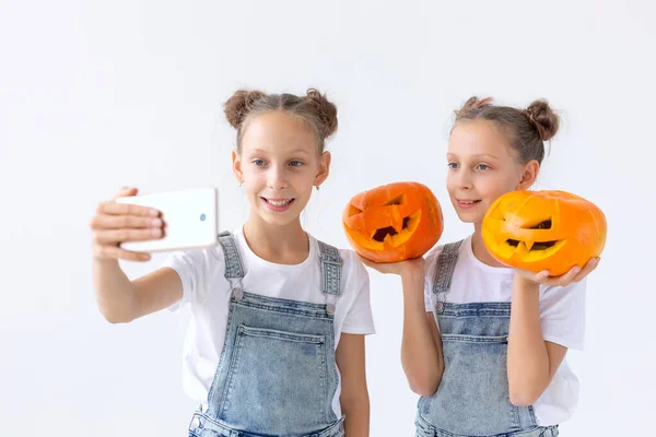 Buon Halloween, vacanze e concetto di infanzia - Carino gemelle sorelle ragazze con una zucca Jack-o-lanterna divertirsi mentre trascorre del tempo in casa — Foto Stock