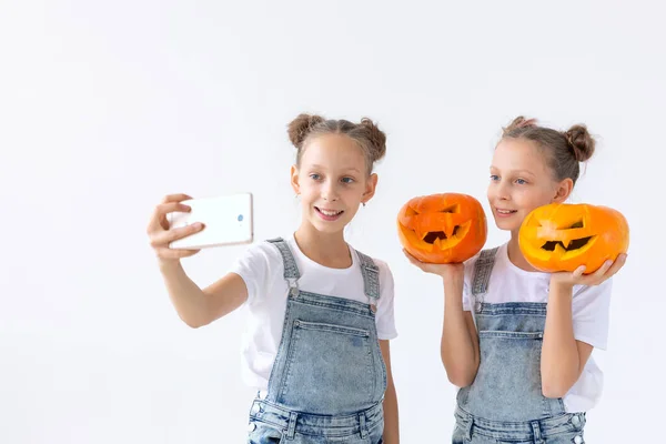 Buon Halloween, vacanze e concetto di infanzia - Carino gemelle sorelle ragazze con una zucca Jack-o-lanterna divertirsi mentre trascorre del tempo in casa — Foto Stock