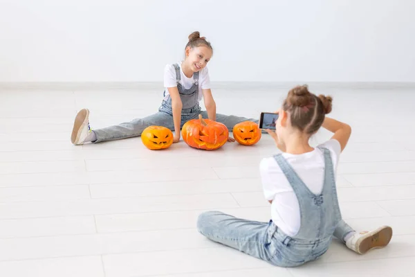 Buon Halloween, vacanze e concetto di infanzia - Carino gemelle sorelle ragazze con una zucca Jack-o-lanterna divertirsi mentre trascorre del tempo in casa — Foto Stock