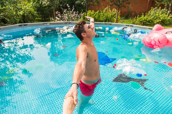 Ecologie, plastic afval, milieu nood en watervervuiling-Guy leiden in een zwembad met vuilnis — Stockfoto