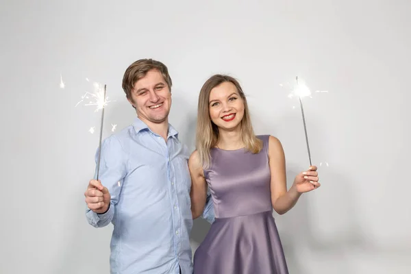 Conceito de celebração, festa e feriado - Homem e mulher felizes abraçando sobre fundo cinza com sparklers — Fotografia de Stock