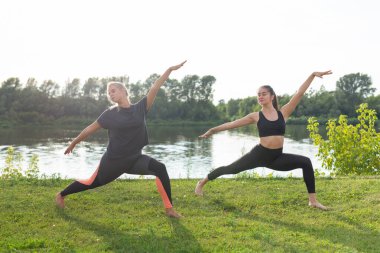 Uyum ve sağlıklı yaşam tarzı konsepti - Spor giyim genç ince kadınlar yoga açık havada pratik.